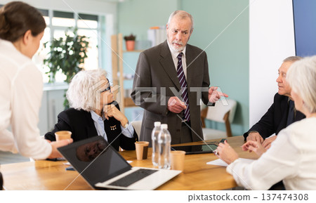 Male boss reprimanding upset subordinates sitting at table in office meeting room, expressing dissatisfaction with work 137474308
