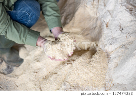 Farmer holds a handful of cornmeal in his hands - feed for cows and other animals on farm Farmer holds a handful of cornmeal in his hands - feed for cows and other animals on farm 137474388