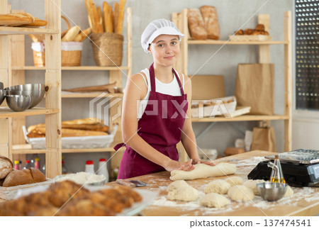 Teenage girl rolls out dough in bakery Teenage girl rolls out dough in bakery 137474541