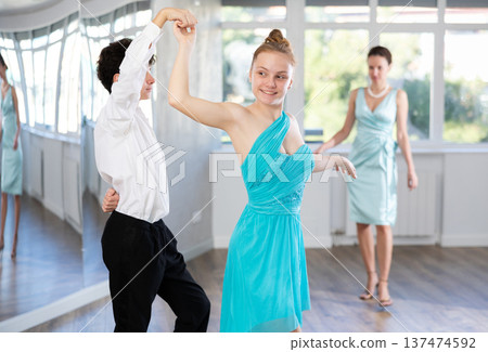Couple of teenagers in evening dresses are learning to dance an polonaise dance 137474592