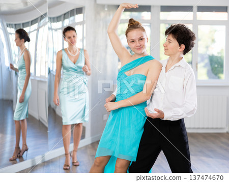 Teenage girl and boy practicing waltz in dance hall with female mentor 137474670