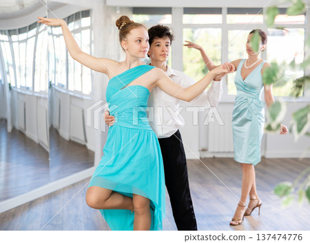 Dance teacher teaches a girl and a boy couples ballroom dancing 137474776