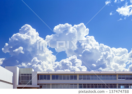 A nostalgic panoramic view of the school building during summer vacation, with large cumulonimbus clouds rising in the bright blue sky. 137474788