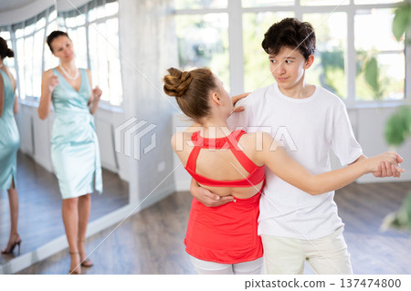 Teenage girl and boy practicing waltz in dance hall with female mentor 137474800