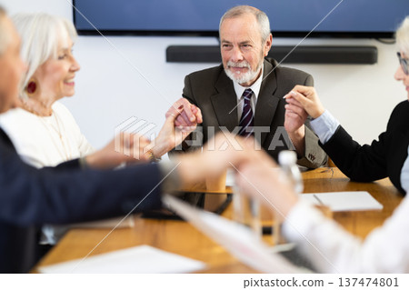 General handshake, with senior business participants holding hands and smiling happily 137474801