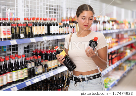 Young woman choosing soy sauce in store 137474928