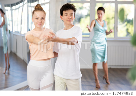 Teenage girl and boy practicing waltz in dance hall with female mentor Teenage girl and boy practicing waltz in dance hall with female mentor 137474988