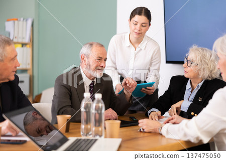 Female secretary gives folder with documents to elderly man 137475050