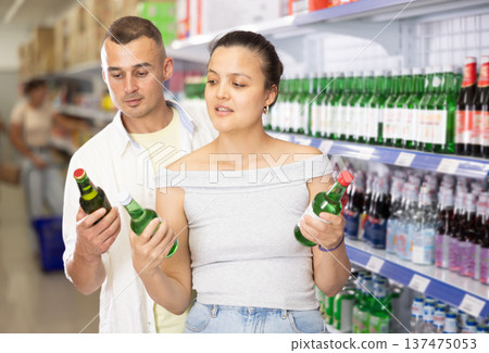 Positive couple choosing alcoholic drinks at local Asian store Positive couple choosing alcoholic drinks at local Asian store 137475053