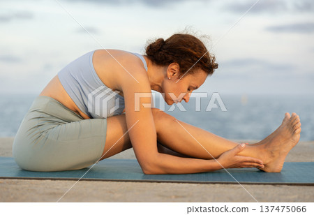 Warm-up and stretching of the body before yoga classes on ocean shore Warm-up and stretching of the body before yoga classes on ocean shore 137475066