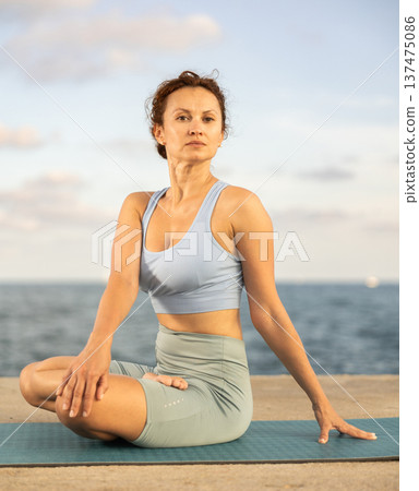 Yoga practice on embankment, female athlete fulfil carry out padmasana svastikasana, Siddhasana Yoga practice on embankment, female athlete fulfil carry out padmasana svastikasana, Siddhasana 137475086