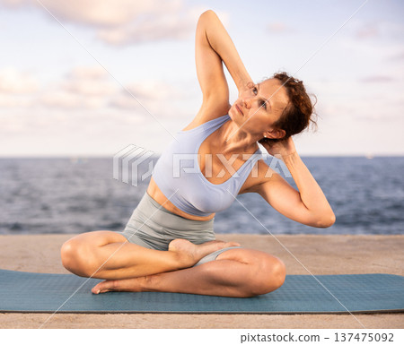 Yoga practice on embankment, female athlete fulfil carry out padmasana svastikasana, Siddhasana Yoga practice on embankment, female athlete fulfil carry out padmasana svastikasana, Siddhasana 137475092