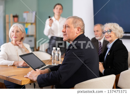 Young woman gives presentation to group of eldery employees Young woman gives presentation to group of eldery employees 137475371
