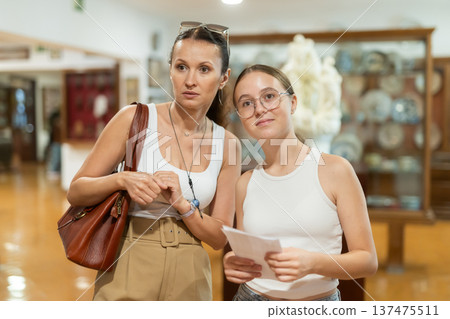 Young woman with teen daughter walk around museum, cookware zone. Young woman with teen daughter walk around museum, cookware zone. 137475511