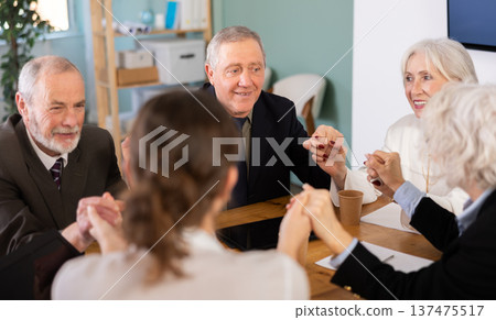 Team of seniors hold hands before starting work Team of seniors hold hands before starting work 137475517