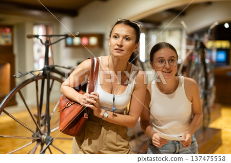 Woman and teenage girl looking at vintage bicycles in museum 137475558