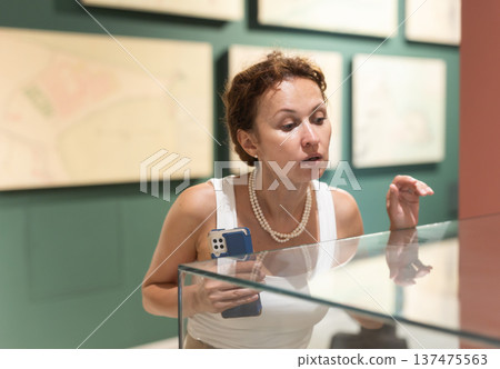 Woman observing artifacts inside glass display case at museum 137475563