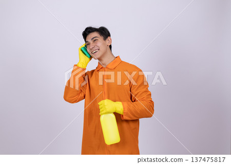 Young man in orange work uniform using spray bottle Young man in orange work uniform using spray bottle 137475817