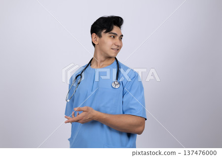 Male doctor in blue scrubs gesturing to the side 137476000