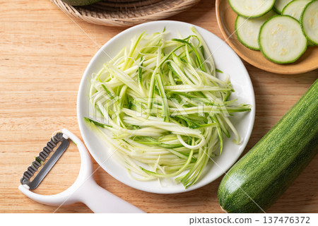 Top view of fresh zucchini noodles (zoodles) in a white plate, prepared for healthy cooking Top view of fresh zucchini noodles (zoodles) in a white plate, prepared for healthy cooking 137476372