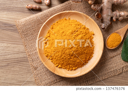Turmeric powder in a wooden bowl with a wooden spoon and fresh turmeric roots. Organic healthy spice Turmeric powder in a wooden bowl with a wooden spoon and fresh turmeric roots. Organic healthy spice 137476376