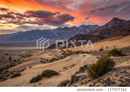 Breathtaking Sunset Over Sand Dunes in Mountainous Desert Landscape 137477162