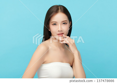 A beautiful young Asian woman with clean, fresh skin against a blue background. Skincare, facial treatment, cosmetology, beauty, and spa. An elegant portrait of an Asian woman. A beautiful young Asian woman with clean, fresh skin against a blue background. Skincare, facial treatment, cosmetology, beauty, and spa. An elegant portrait of an Asian woman. 137478666