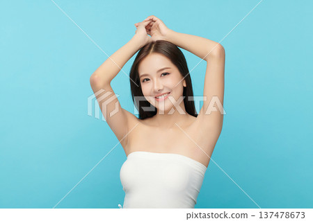 Beautiful Young Asian woman Raises her hands to Showcase clean and hygienic underarms Against a blue background, Smooth armpit cleanliness and protection concept 137478673