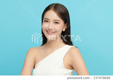 A beautiful young Asian woman with clean, fresh skin against a blue background. Skincare, facial treatment, cosmetology, beauty, and spa. An elegant portrait of an Asian woman. A beautiful young Asian woman with clean, fresh skin against a blue background. Skincare, facial treatment, cosmetology, beauty, and spa. An elegant portrait of an Asian woman. 137478680