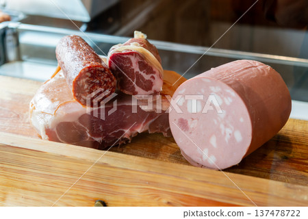 Beautiful cross-sections of mortadella and salami blocks, large pieces of bologna sausage and chunks of prosciutto, arranged as a food background material 137478722