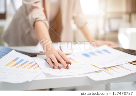 Close up of a businesswoman or office worker's hand holding pencil over document with graph or chart 137478787