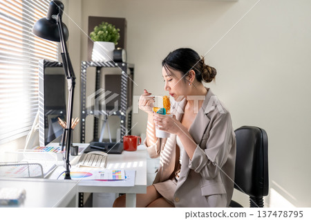 Pretty asian businesswoman office worker enjoy eating instant noodle at computer table with sunlight Pretty asian businesswoman office worker enjoy eating instant noodle at computer table with sunlight 137478795
