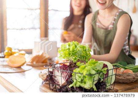 Close up of blurred woman friends cooking with fresh lettuce vegetable ingredient at kitchen counter Close up of blurred woman friends cooking with fresh lettuce vegetable ingredient at kitchen counter 137478979