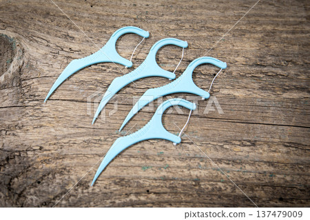 Four Dental Floss Picks Arranged On Rustic Wooden Surface Closeup Four Dental Floss Picks Arranged On Rustic Wooden Surface Closeup 137479009
