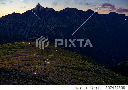 從雙六山眺望北阿爾卑斯山脈、槍岳以及黎明時分登山者的燈光。 從雙六山眺望北阿爾卑斯山脈、槍岳以及黎明時分登山者的燈光。 137479268