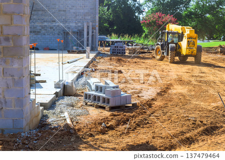 Workers are using heavy machinery arranging building materials at construction site 137479464