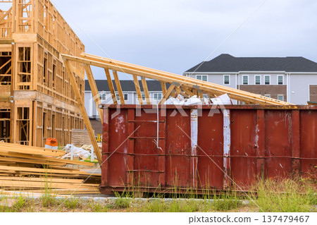 Workers are building new structure while dumpster collects waste materials near construction site. Workers are building new structure while dumpster collects waste materials near construction site. 137479467