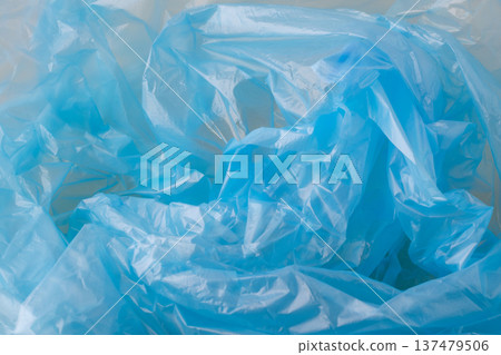 Crumpled blue plastic material forming an abstract background texture. Showing translucent, synthetic, and reusable plastic packaging Crumpled blue plastic material forming an abstract background texture. Showing translucent, synthetic, and reusable plastic packaging 137479506