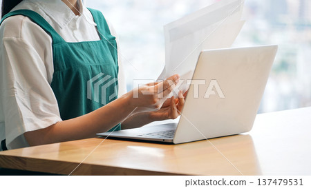Restaurant clerk entering data on a laptop 137479531