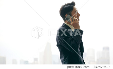 一位男性商務人士在智慧型手機上交談,背景是一座城市 一位男性商務人士在智慧型手機上交談,背景是一座城市 137479608