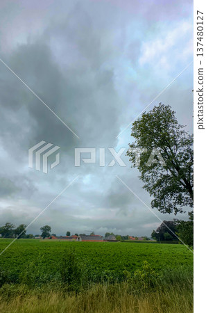Dark clouds cover verdant fields and remote countryside village 137480127