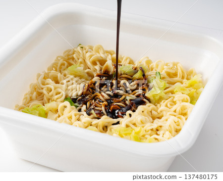 將醬汁淋在炒麵杯上 將醬汁淋在炒麵杯上 137480175