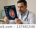 A male physician evaluates an AI-enhanced MRI scan of a heart on a digital screen. He is focused and surrounded by clinical decor in a modern medical setting. 137481546
