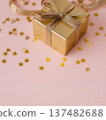 Gift box on pink surface surrounded by golden stars 137482688