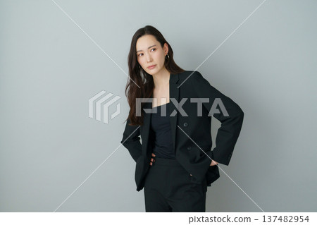 Fashion portrait of a young Japanese woman in a black suit on a gray background Fashion portrait of a young Japanese woman in a black suit on a gray background 137482954