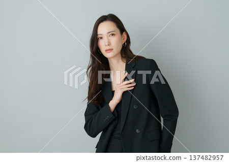灰色背景上的年輕日本女性身穿黑色西裝的時尚肖像 灰色背景上的年輕日本女性身穿黑色西裝的時尚肖像 137482957