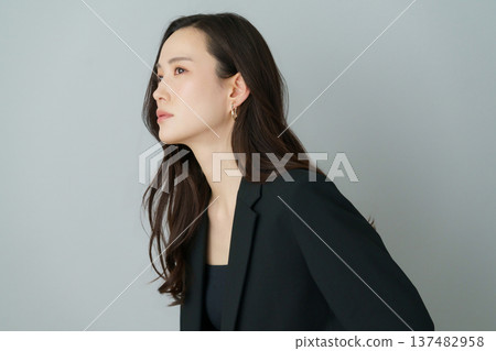 灰色背景上的年輕日本女性身穿黑色西裝的時尚肖像 灰色背景上的年輕日本女性身穿黑色西裝的時尚肖像 137482958