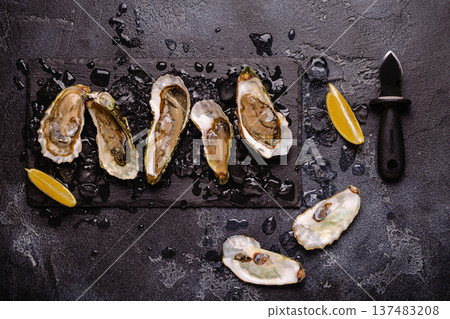 Opened fresh oysters on a plate, served with lemon and ice. Opened fresh oysters on a plate, served with lemon and ice. 137483208