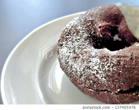 Close-up of a chocolate donut on a white plate 137485476