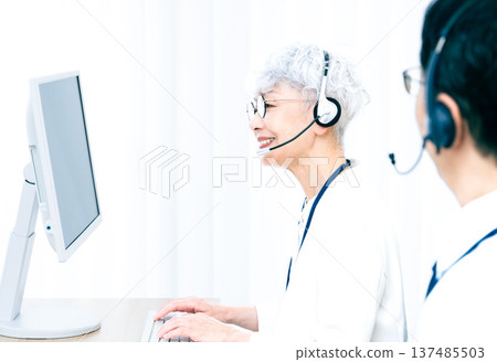 一位戴著耳機的老婦人正在操作電腦。 137485503